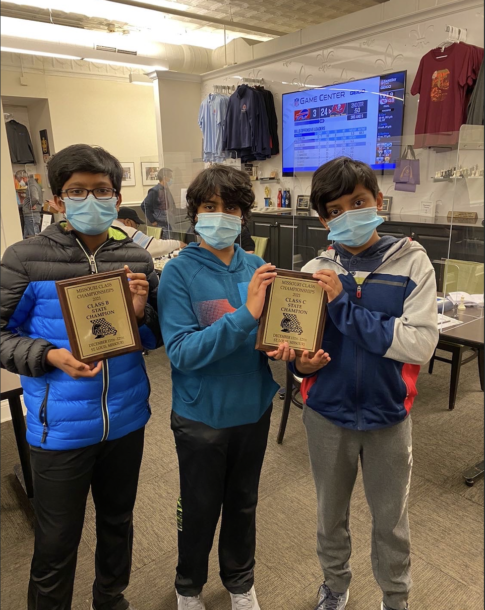 Three young chess players holding Missouri Class Championship state champion plaques
